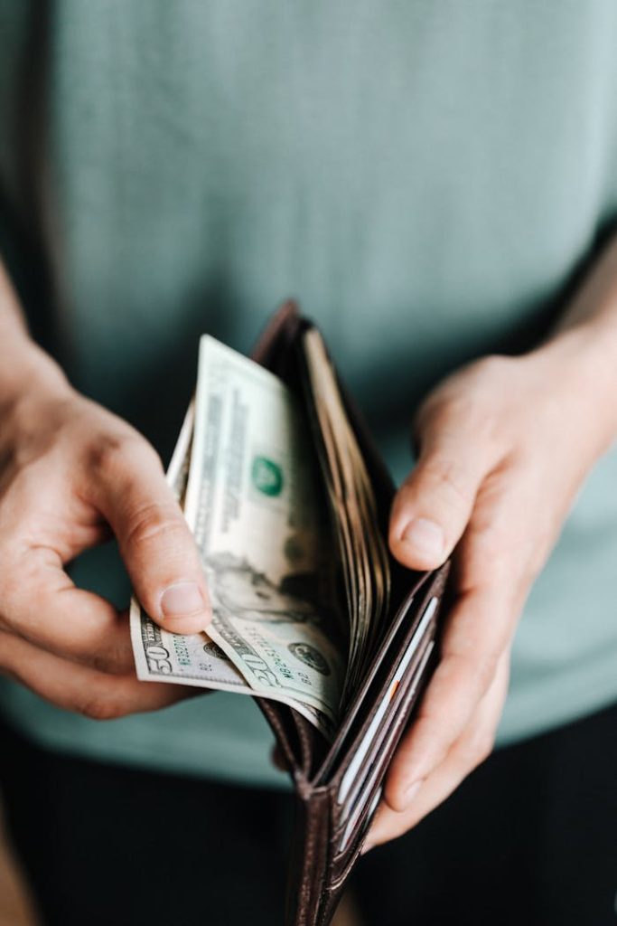 pexels photo 4386433 Close-up of hands holding a wallet with cash, depicting financial management.