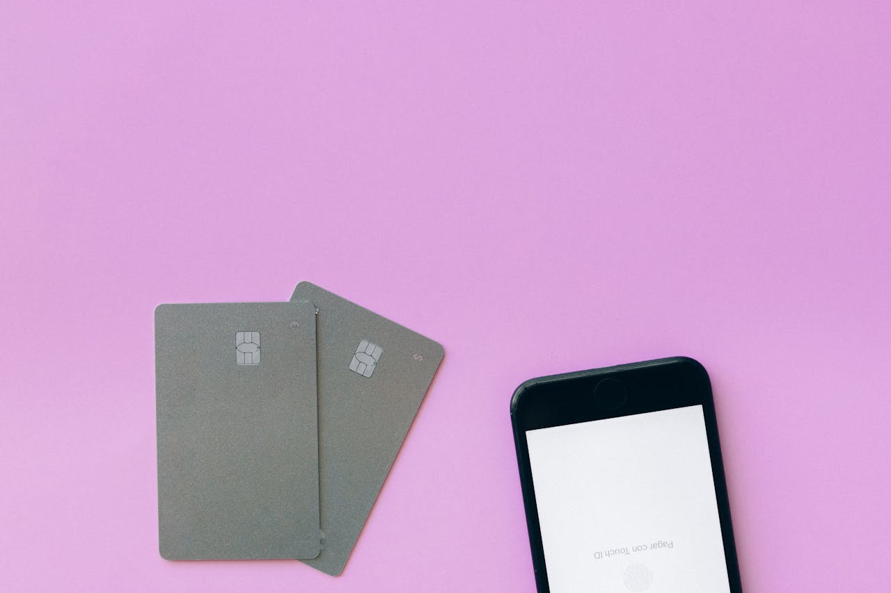 heros-img Flat lay of credit cards and smartphone on pink surface, symbolizing digital payment solutions.